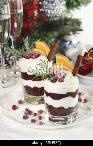 Weihnachts-Cranberry-Dessert-Tiramisu mit Mascarpone und Schlagsahne, Schokoladen-Kekskrümel und Cranberry-Marmelade, garniert mit Orangenscheiben, Dose Stockfoto