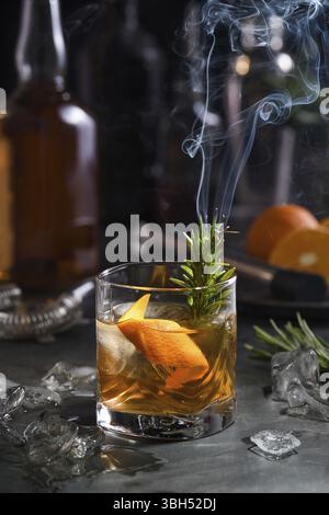 Cocktail Old Fashioned Negroni. Die Adstringenz des Whiskeys wird durch Zucker ausgeglichen, und die Kräutertinktur und der rauchende Rosmarin geben Geschmack und Ursprung hinzu Stockfoto