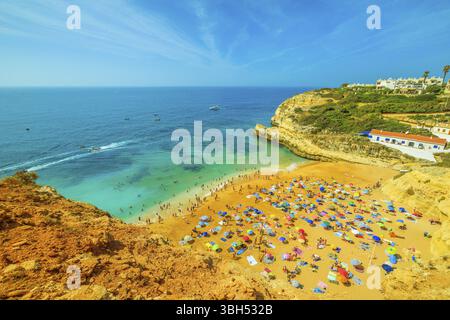 Aus der Vogelperspektive der goldenen Klippen von Praia de Benagil, Algarve in der Nähe der Lagoa, Portugal, Europa. Touristen sonnen sich am berühmten Strand von Benagil, für den bekannt ist Stockfoto