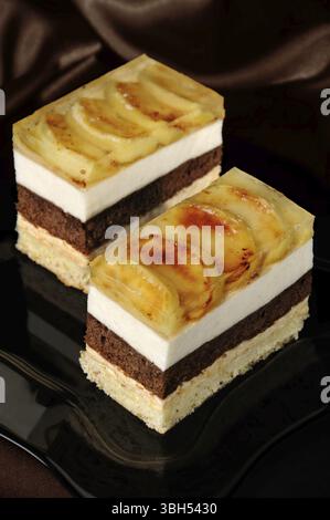 Kuchen aus Karamell, Apfel Mousse, Schokolade und Mandeln Biskuit mit einer Schicht Gelee karamellisiertem Apfel Scheiben gestapelt Stockfoto