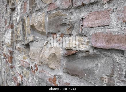 Alte Mauer aus unregelmässigen Steinen mit warmen Farben Stockfoto