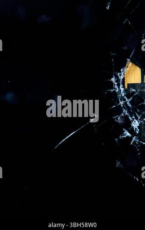 Schwarzweißfoto eines Fensters mit einem defekten Fensterbereich. Das Fenster befindet sich vor einem Gebäude mit gelbem Dach. Das Foto hat ein stimmungsvolles und düsteres Gefühl Stockfoto