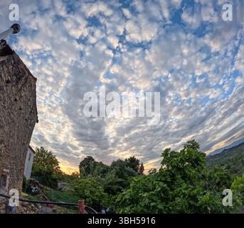 Der Himmel ist voller weißer Wolken, von einem Gebäude aus gesehen, das über die Berge blickt. Stockfoto