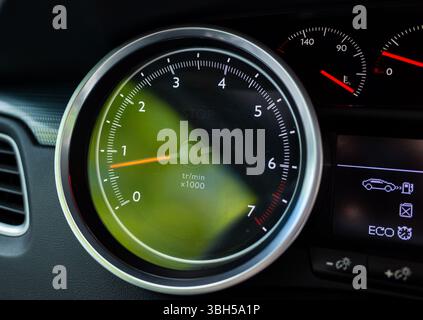 Hochauflösende Nahaufnahme eines modernen Pkw-Drehzahlmessers, der die Umdrehungen pro Minute (U/min) in einem Armaturenbrett anzeigt, wobei das Eco-Modus-Display teilweise sichtbar ist. Suita Stockfoto