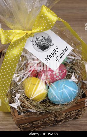 Bunte Eier gestapelt Heu in Cellophangeschenkkorb zu Ostern Stockfoto
