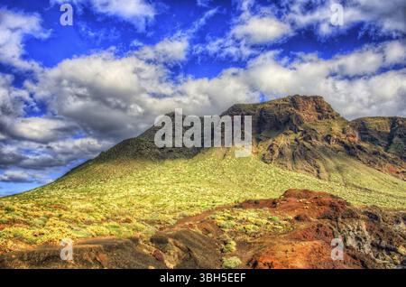 Wolken am blauen Himmel und grüne Felder mit Bergen am sonnigen Tag, Nordwestküste Teneriffas in der Nähe des Leuchtturms Punto Teno, Canaria Stockfoto