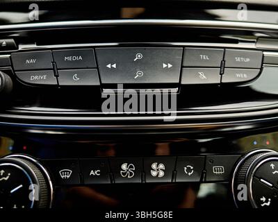 Das Armaturenbrett des Fahrzeugs verfügt über viele Tasten und Schalter, darunter eine Medientaste. Die Tasten sind schwarz und die Schalter sind weiß Stockfoto