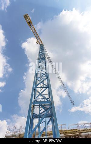 Gebäude mit Kränen im Bau. Baustelle vor blauem Himmel mit Wolken. Ansicht von unten Stockfoto
