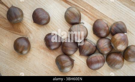 Kastanien, die verstreut auf einem Holztisch, von oben gesehen Stockfoto