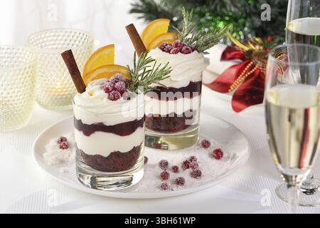 Weihnachts-Cranberry-Dessert-Tiramisu mit Mascarpone und Schlagsahne, Schokoladen-Kekskrümel und Cranberry-Marmelade, garniert mit Orangenscheiben, Dose Stockfoto
