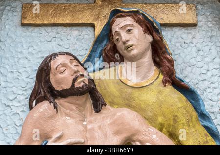 Religiöse Steinstatue in Farbe, die das Mitleid Michelangelos darstellt. Maria Mutter hält Jesus Christus auf ihrem Schoß nach der Kreuzigung Stockfoto