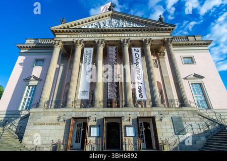 Vorderansicht der Deutschen Staatsoper in Berlin mit Bannern und klassischer Architektur unter einem hellblauen Himmel. Stockfoto