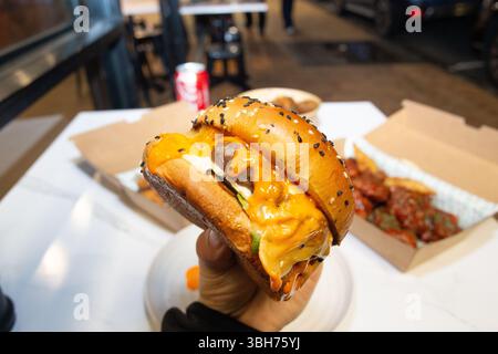 Koreanische, tiefgetrocknete, scharfe rote Hähnchensauce in einer Papierkarton zum Mitnehmen. Stockfoto