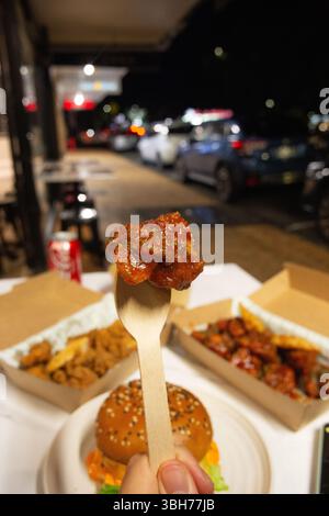 Koreanische, tiefgetrocknete, scharfe rote Hähnchensauce in einer Papierkarton zum Mitnehmen. Stockfoto