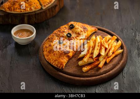 Italienische Calzone mit Pommes frites auf dunklem Hintergrund Stockfoto