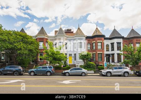 Washington D.C., USA, 24. Mai 2025. Farbenfrohe historische Reihenhäuser mit Türmchen und Erkerfenstern säumen eine sonnige Straße im Viertel Adams Morgan. Stockfoto
