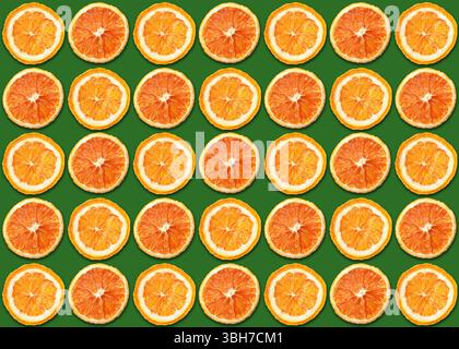 In Scheiben geschnittenes orangefarbenes Muster. Helle saftige Zitrusscheiben auf grünem Hintergrund. Farbenfrohe symmetrische Komposition. Frische Vitaminfrucht-Textur für Sommerdesign. Stockfoto