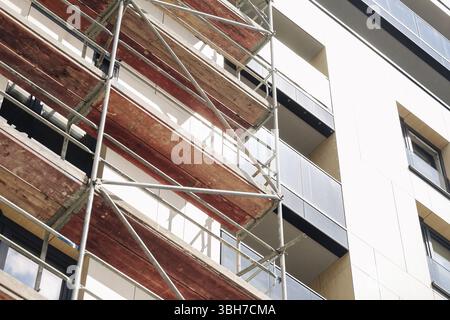 Gerüste in einem modernen Gebäude. Baustelle mit Metallplattformen. Stadtsanierungsprojekt läuft. Provisorische Fassadenreparatur. Stockfoto