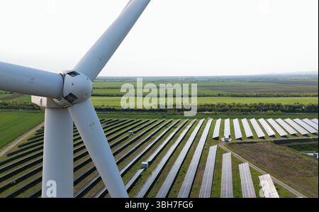 Nahaufnahme der Windkraftanlage mit Solarkraftwerk im Hintergrund. Stockfoto