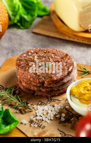 Rohes Rindfleisch-Burger-Patty, gewürzt und fertig Stockfoto