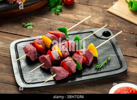 Kalbsschaschaschenspieße mit Gemüse, bereit zum Grillen, Holzoberfläche. Stockfoto