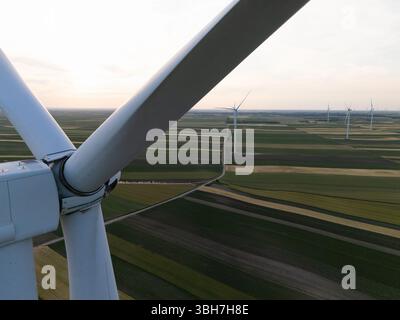 Luftaufnahme einer Windkraftanlage auf einer landwirtschaftlichen Feilablage bei Sonnenuntergang. Nahaufnahme der Klingen. Stockfoto