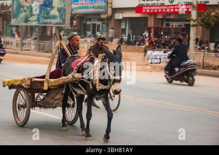 Ein Alter Mann zu reiten, ein Maultier und Wagen um den Sonntag Basar in Kashgar, Provinz Xinjiang, China Stockfoto