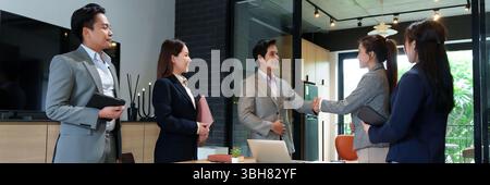 Asiatische Erwachsene Geschäftsmänner und Geschäftsfrauen Handschlag im Büro. Selbstbewusster Handschlag zwischen Partnern während eines Meetings. Geschäftsabschluss mit Success Stockfoto
