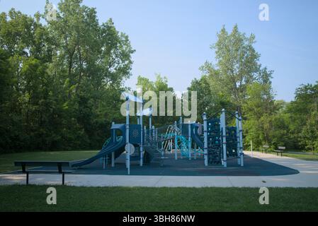 Moderner blauer Spielplatz in einer üppigen grünen Park-Umgebung Stockfoto