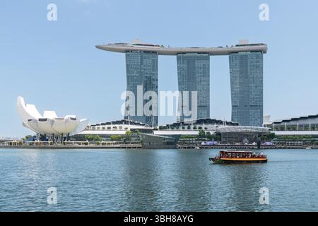 Das Marina Bay Sands Hotel und das Art Science Museum gegenüber dem Marina Reservoir mit einem Touristenboot, Singapur Stockfoto