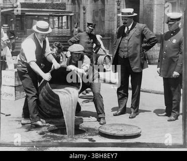 Der stellvertretende New Yorker Polizeikommissar John A. Leach, richtig. Er beobachtete Agenten, wie sie Alkohol in die Kanalisation gießen, nach einem Überfall während der Prohibition um 1921. Archiv amerikanische Fotografie des Alkoholverkaufs 1920er Jahre Beachten Sie, dass das Originalbild leicht verändert und auf Unvollkommenheit abgeschnitten wurde. Stockfoto