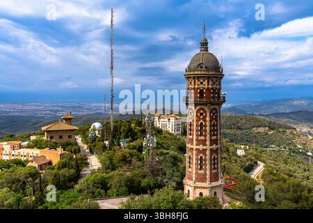 Blick auf den Wasserturm Torre de Les Aigues de Dos Rius auf dem Hügel Tibidabo im Vergnügungspark im Sommer, mit mediterranem Meer im Hintergrund, Bar Stockfoto