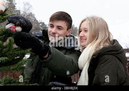 Ein Paar lacht und schmückt den Weihnachtsbaum Stockfoto