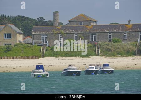 Vier kleine Boote in der Nähe des Strandes vor traditionellen Häusern in idyllischer Umgebung, Tresco, Scilly-Inseln, Cornwall, England, Vereinigtes Königreich, Stockfoto