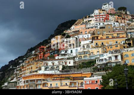 Schwindelerregende, auf Klippen sitzende Gebäude mit einer lebhaften Palette von Pastelltönen ragen steil über das schicke und lebhafte Positano, Amalfiküste, Süditalien Stockfoto