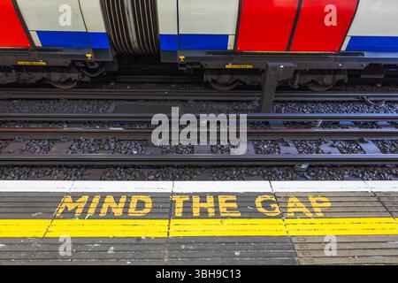 Legendäres MIND THE GAP-Schild auf der London Tube Platform, Sicherheitsschild und Zug Stockfoto