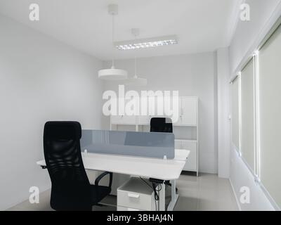 Foto von modernem weiß sauberem neuen Arbeitsplatzdesign, Dekoration mit Möbeln, schwarzen ergonomischen Stühlen und Tablettentrennwand, elektrische Höhenanpassung Stockfoto