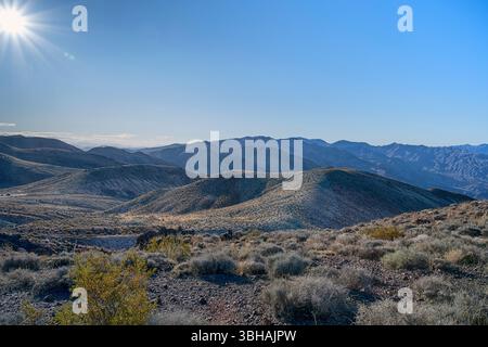 Die raue Schönheit der felsigen Wüstenlandschaft des Death Valley National Park mit aufgehender Sonne und blauem Himmel im Hintergrund. Stockfoto