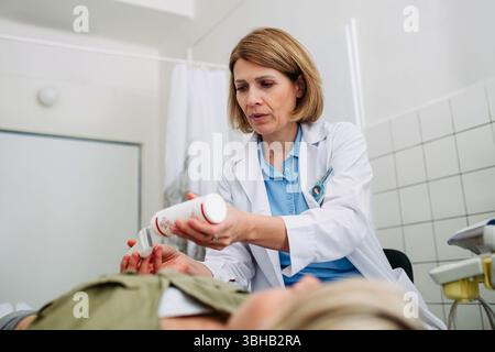 Radiologe, der vor der Abdomen-Untersuchung Gel auf die Ultraschallsonde aufträgt Stockfoto