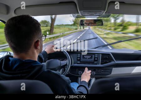 Innenansicht des Fahrzeugs. Fahrer und Beifahrer. Regnerische Straße. Stockfoto