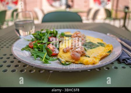 Gourmet, nahrhaftes und herzhaftes Mittagessen oder Frühstück mit Spinat-Omelette mit Lachs-Tartar und einem frischen Rucola-Salat auf a c Stockfoto