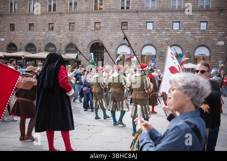 Florenz, Italien, 04.16.2025: Ritterprozession durch das Zentrum einer italienischen Stadt. Eine Prozession in historischen Kostümen mit Fahnen geht durch Stockfoto