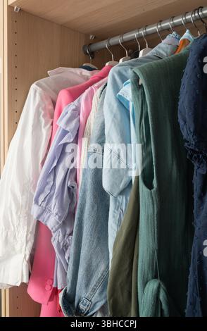 Eine gut organisierte Garderobe mit einer lebendigen Auswahl an farbenfrohen Hemden und stylischen Blusen in verschiedenen Designs Stockfoto
