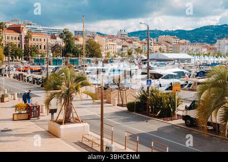 Cannes, Frankreich - 9. Mai 2025: Der Quai Saint-Pierre im Alten Hafen von Cannes, mit Anlegejachten, dem Rathaus auf der linken Seite und den weißen Zelten von Cannes Stockfoto