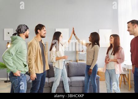 Gesellschaft von multiethnischen Freunden, die sich treffen, haben fröhliche Ausdrücke und machen hohe fünf Gesten Stockfoto
