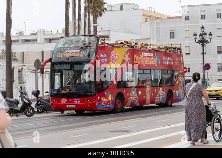 Cadiz, Andalusien, Spanien - 9. Juni 2025: Roter Doppeldecker Hop-on-Hop-off-Bus der City Sightseeing Tour fährt durch Cadiz in Südspanien, ein beliebtes Transportmittel für Touristen *** Roter Doppeldecker-Hop-on-Hop-off-Bus der City Sightseeing Tour fährt durch Cadiz in Südspanien, ein beliebtes Transportmittel für Touristen Stockfoto