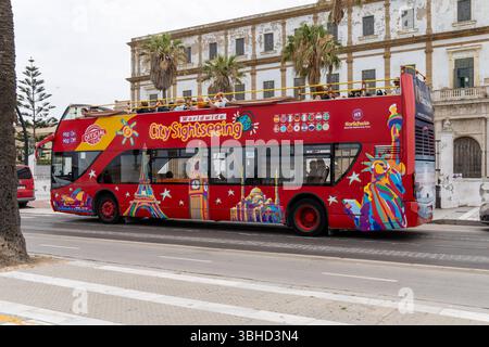 Cadiz, Andalusien, Spanien - 9. Juni 2025: Roter Doppeldecker Hop-on-Hop-off-Bus der City Sightseeing Tour fährt durch Cadiz in Südspanien, ein beliebtes Transportmittel für Touristen *** Roter Doppeldecker-Hop-on-Hop-off-Bus der City Sightseeing Tour fährt durch Cadiz in Südspanien, ein beliebtes Transportmittel für Touristen Stockfoto
