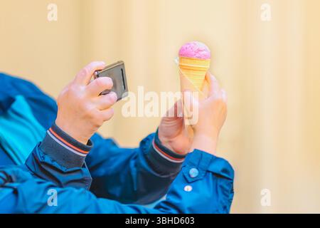 Seniorenpaar macht lustige Selfies und ein Foto von Essen. Person, die ein Smartphone-Foto von in der Hand gehaltenem Eiskegel macht. Konzept von Eis, digital Stockfoto