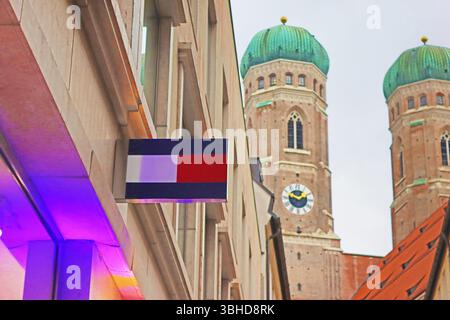 München - 20. Dezember 2023: Tommy Hilfiger-Schild und Frauenkirche Stockfoto