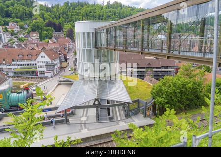 Ein Bahnhof mit moderner Glastür-Überführung in einer kleinen grünen Stadt, Zob-Erweiterung mit Brückenbau für die neue Herman-Hesse-Eisenbahn Stockfoto